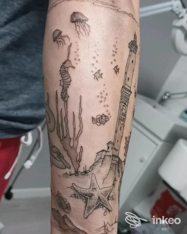 Avambraccio tatuato con motivo marino e faro, foto per God Save The Queen - Tattoo Shop a Monte San Pietro.