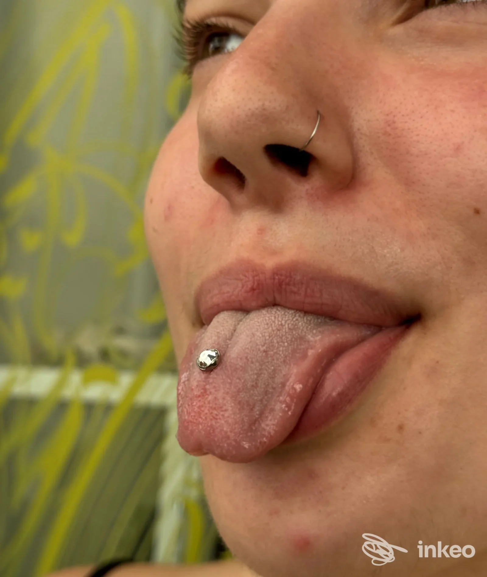 Primo piano di un piercing alla lingua con pallina e anellino al naso, eseguito da Piercer Albert a Rimini.