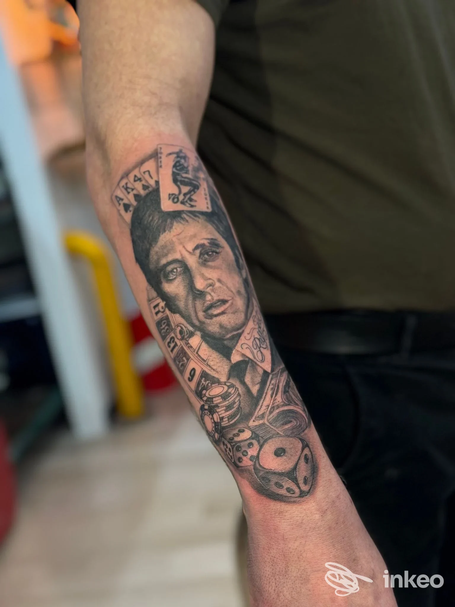 Tatuaggio realistico a inchiostro nero su avambraccio con ritratto e simboli di gioco, Ossa&Koretattoo, Secchiano.