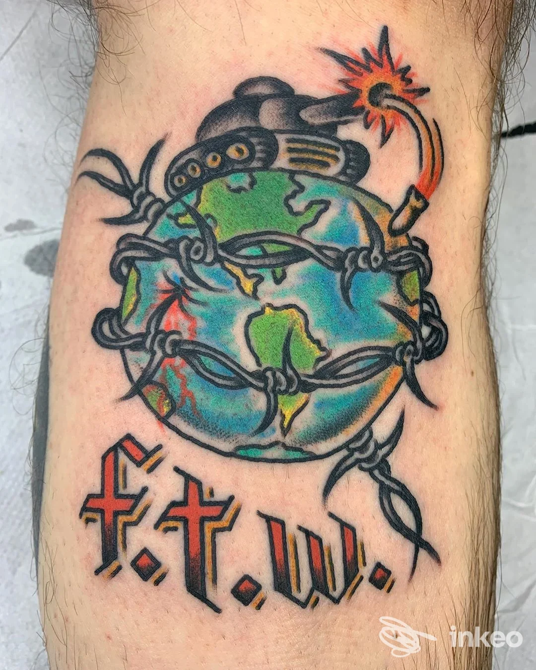 Tatuaggio su avambraccio: globo avvolto da filo spinato con bomba e scritta f.t.w., Franky's Tattoo Shop Piacenza.