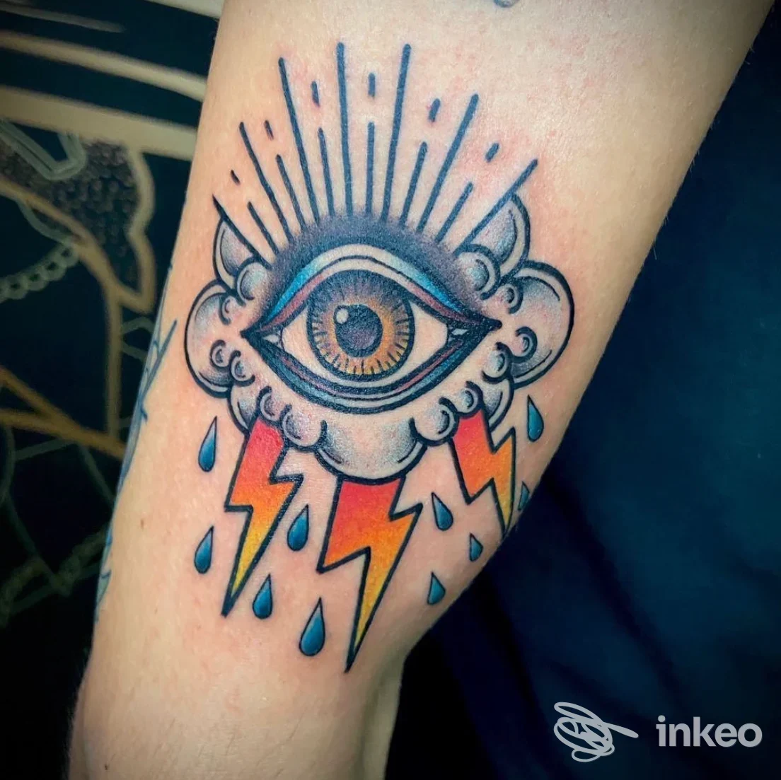 Tatuaggio a colori su avambraccio: occhio stilizzato in una nuvola con fulmini e gocce, foto da Inkspear Store, Modena.