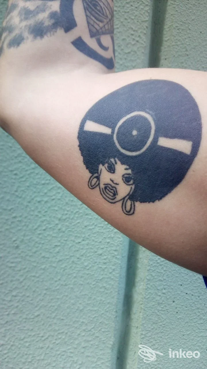 Tatuaggio nero sull'avambraccio interno con volto stilizzato e grande acconciatura; Kiowa Totem Tattoo Studio, Castelfranco Emilia.