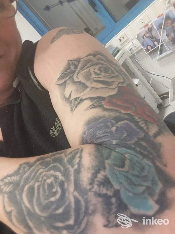 Dettaglio del braccio e avambraccio tatuati con rose e fiori colorati, Kiowa Totem Tattoo Studio, Castelfranco Emilia.