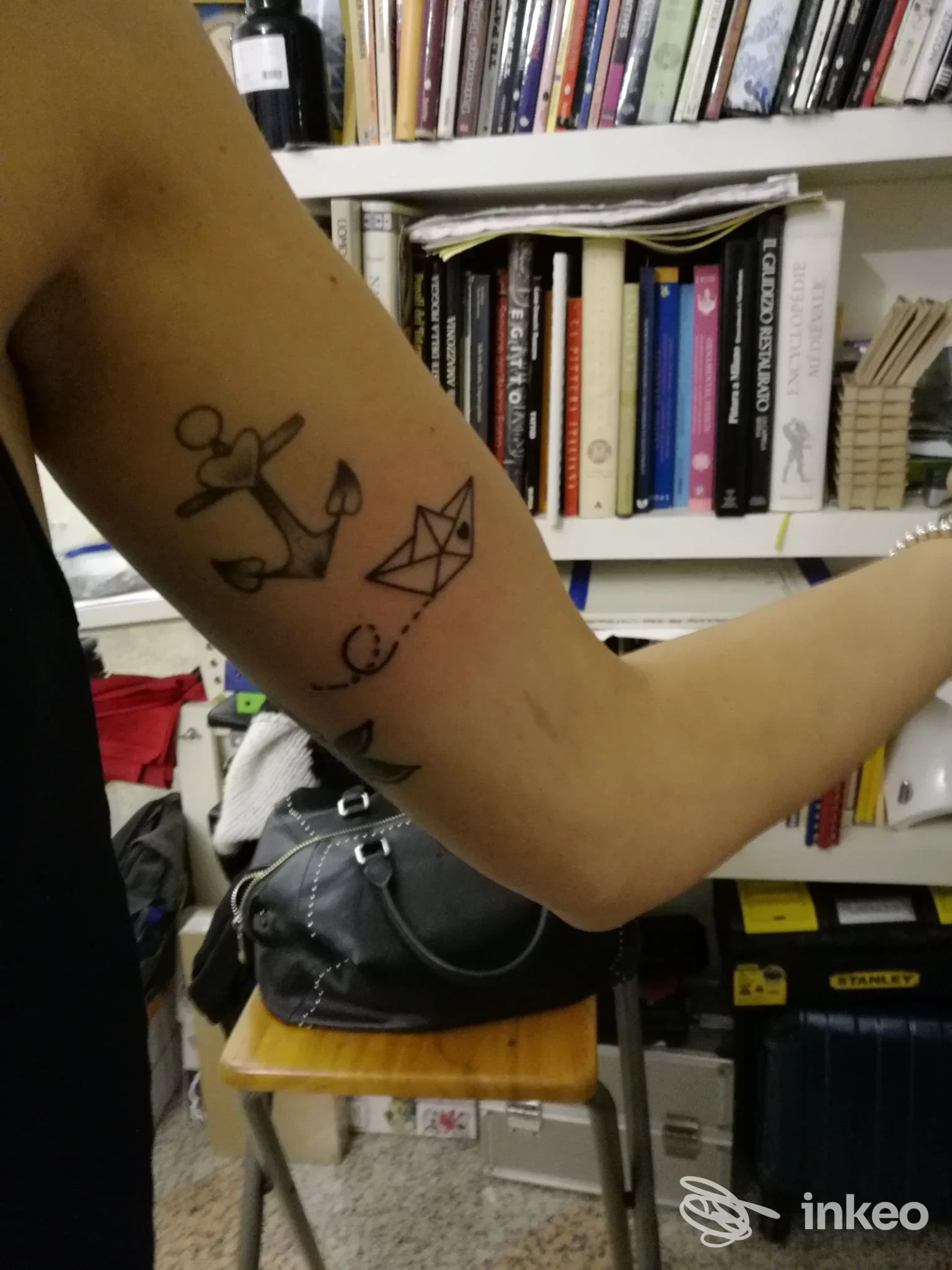 Tatuaggi linework su avambraccio con ancora e barchetta di carta, foto fornita da PMP Tattoo, Piacenza.