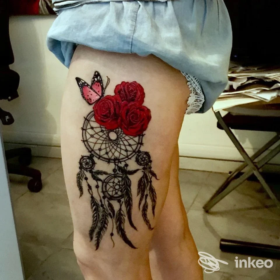 Tatuaggio su coscia con acchiappasogni, tre rose rosse e farfalla, foto per Cheyenne Art Studio Nonantola.
