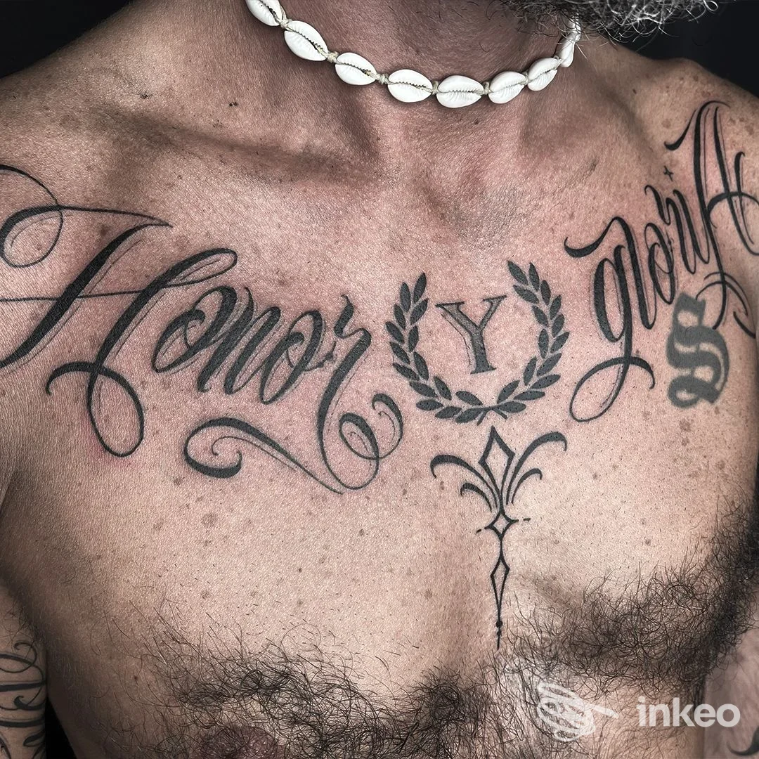 Dettaglio del petto tatuato, lavoro visibile di Sagrado Tattoo a Misano Adriatico, collana di conchiglie e tatuaggi calligrafici neri.