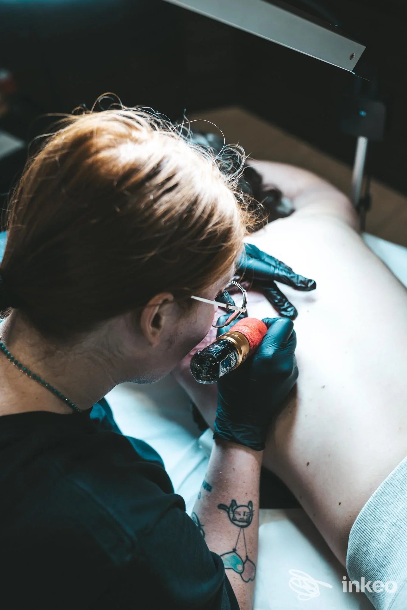 Ritocco di tatuaggio sulla schiena in uno studio: l'artista applica l'inchiostro sulla pelle di un cliente presso Italianink Franciacorta.