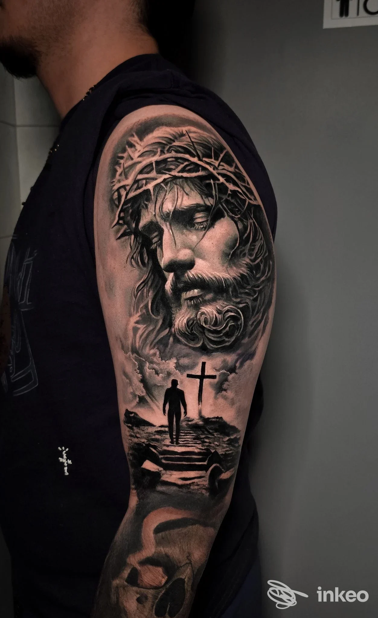 Mezza manica realistico in bianco e nero su braccio con volto religioso e scena della croce, Tattooificio, Piacenza.