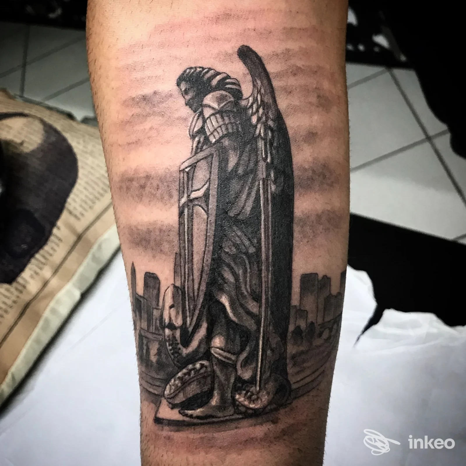 Tatuaggio in bianco e nero di un angelo con scudo sull'avambraccio, Da Dio Tattoo, Gambettola.