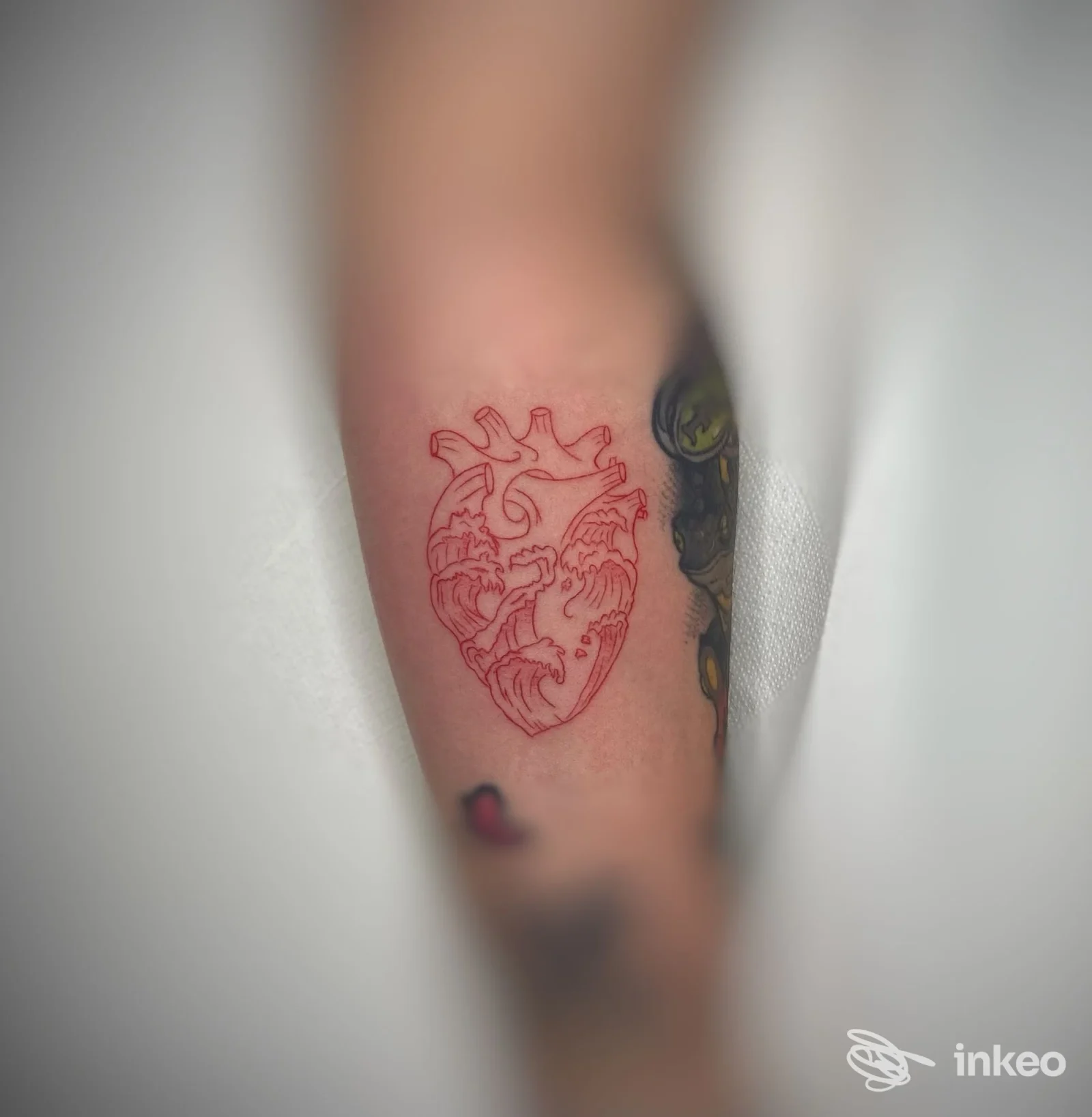 Tatuaggio lineare rosso a forma di cuore anatomico con onde sull'avambraccio, foto realizzata dallo studio DermaUp a Budrio.