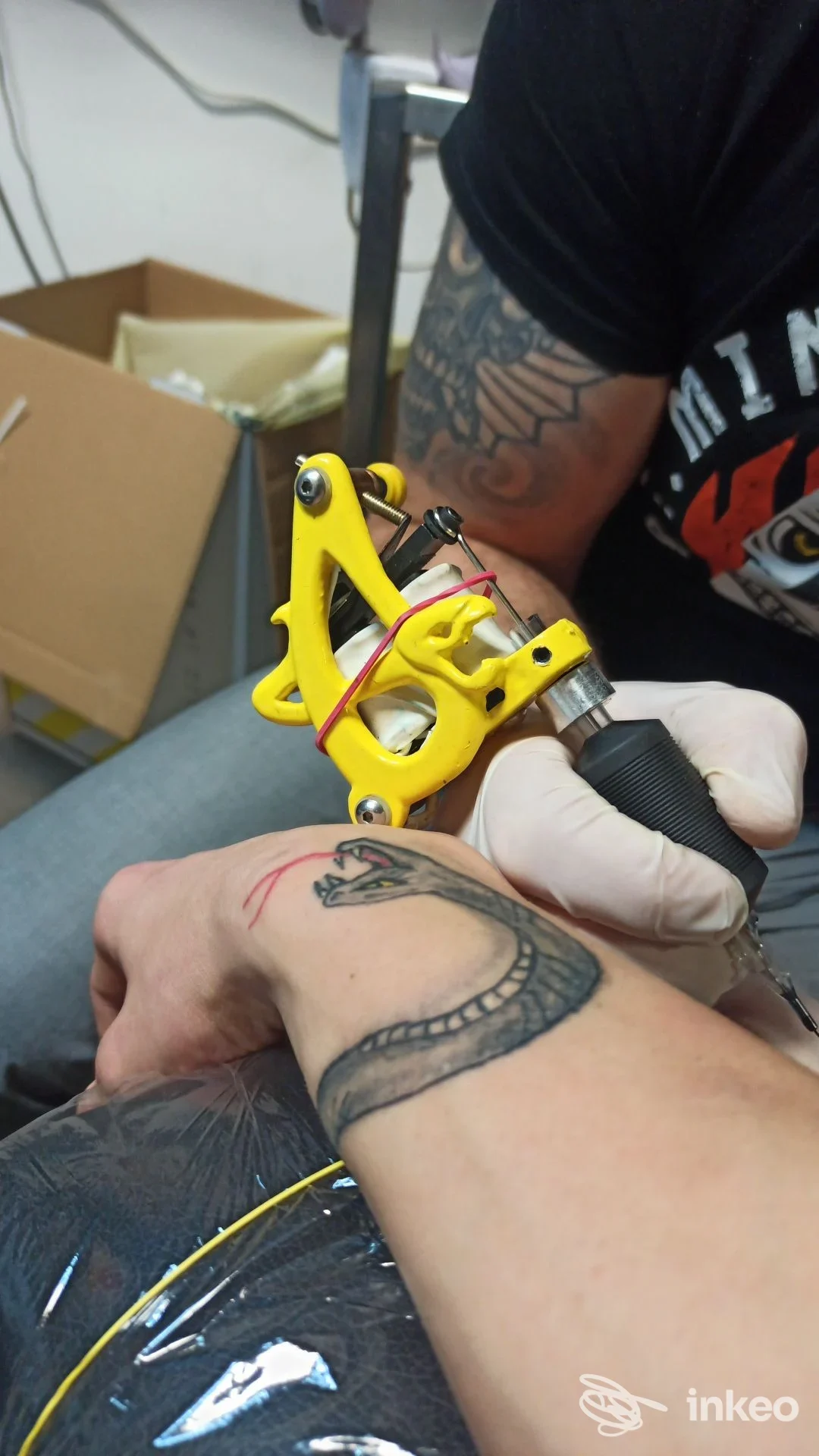 Primo piano di un tatuatore del Snakeman Tattoo & Piercing a Cesenatico che esegue un tatuaggio a forma di serpente sul polso di un cliente.
