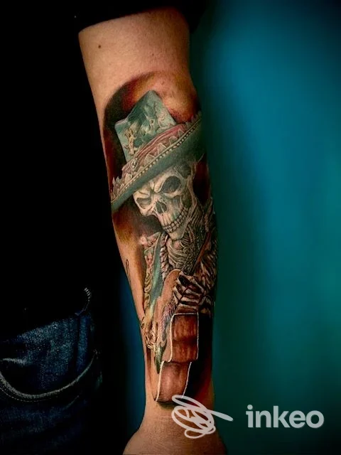 Avambraccio con tatuaggio realistico di uno scheletro con cappello e chitarra, My Karma Tattoo Studio, Carpaneto Piacentino.