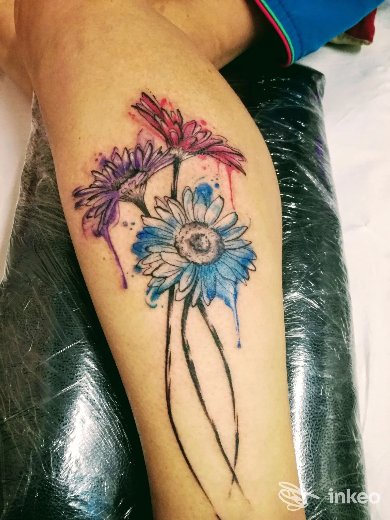 Tatuaggio acquerello di tre margherite colorate sul polpaccio, realizzato da Makablack Tattoo Studio a Cattolica.