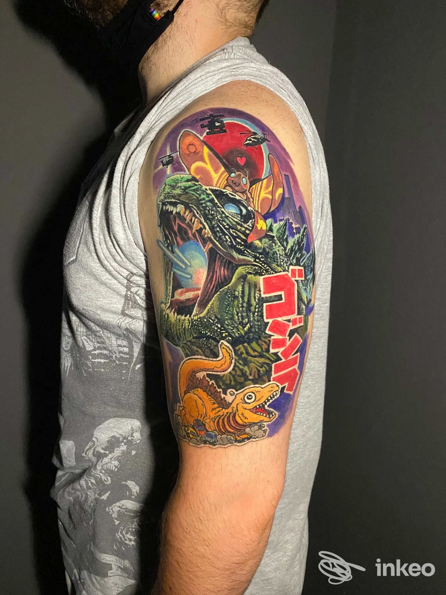 Grande tatuaggio a colori con dinosauri e elementi giapponesi sull'omero di una persona, fotografato per Mörk Tattoo Studio, Parma.