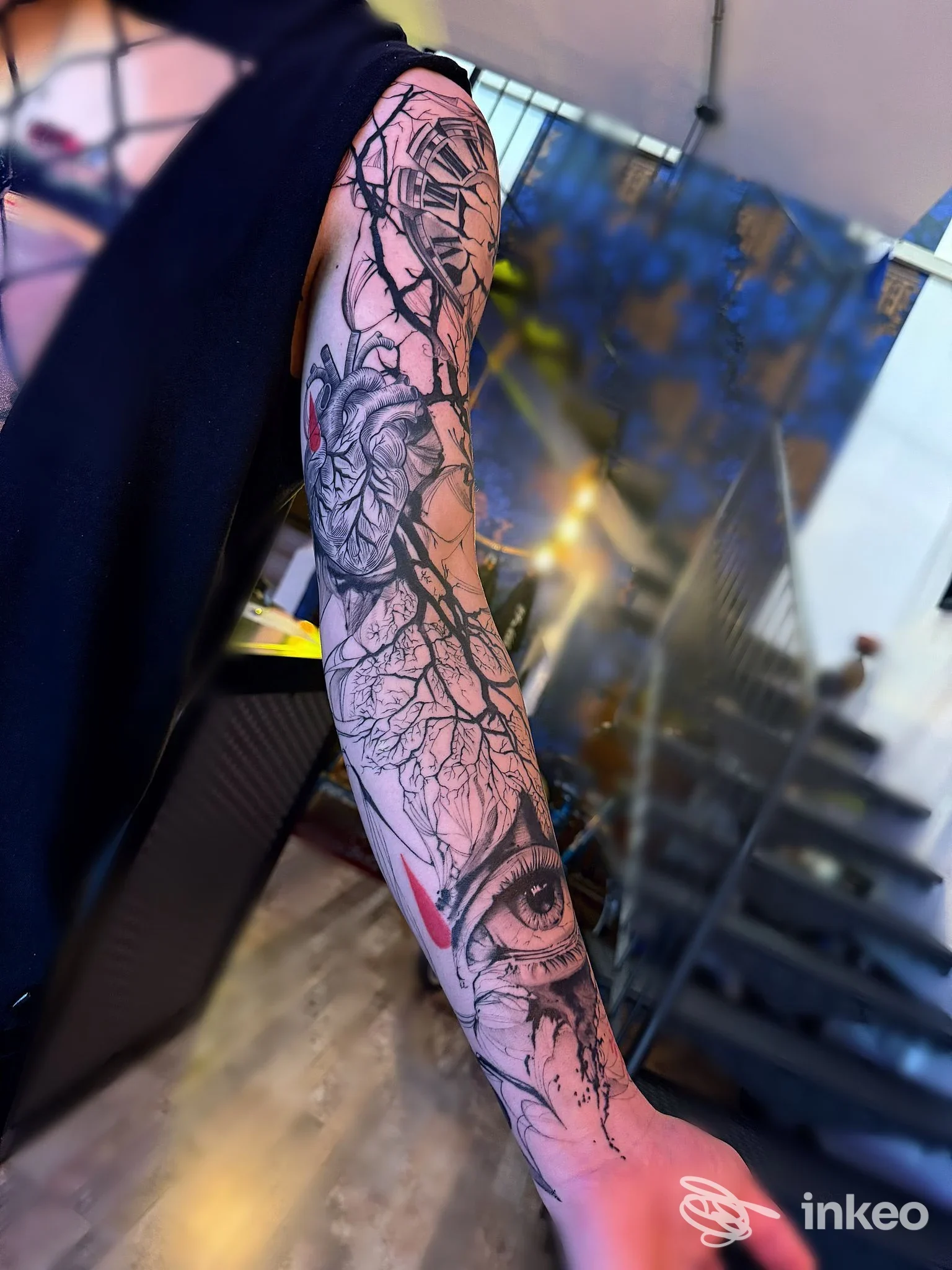 Tattoo visibile su braccio, disegno realistico con linea e ombre, non si vede volto né contenuti promozionali; immagine singola dal contorno urbano.