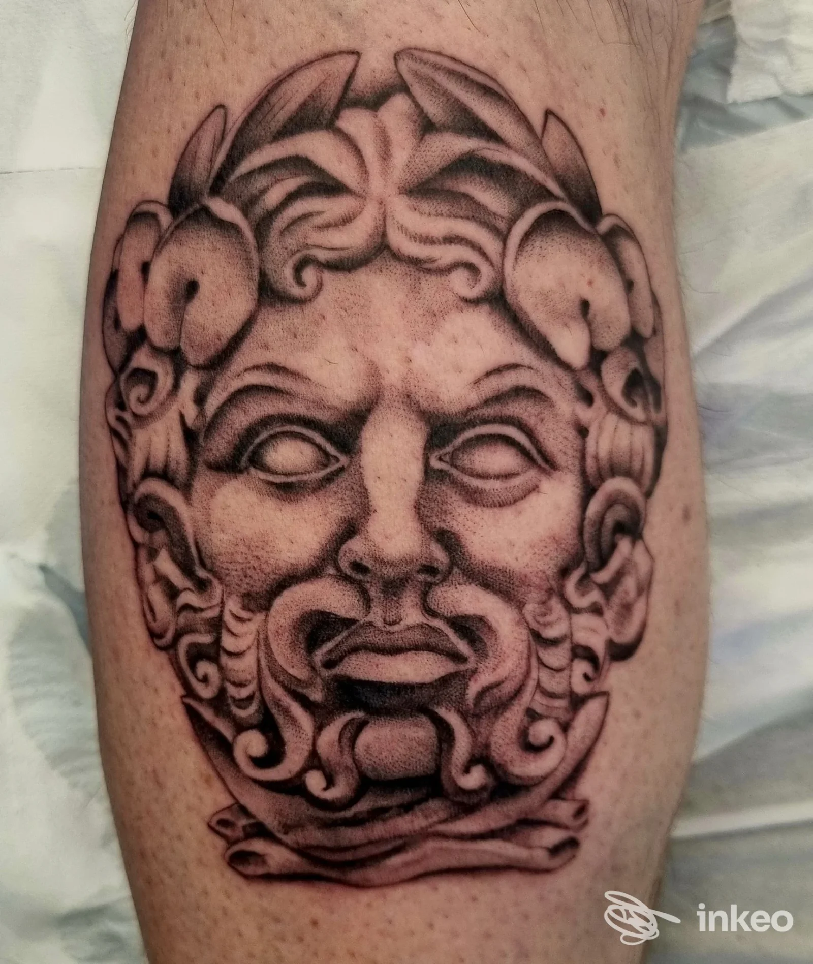 Tatuaggio in bianco e nero raffigurante una maschera classica sul polpaccio, foto di Soul Shop Tattoo a Rimini, dettaglio dell'opera.