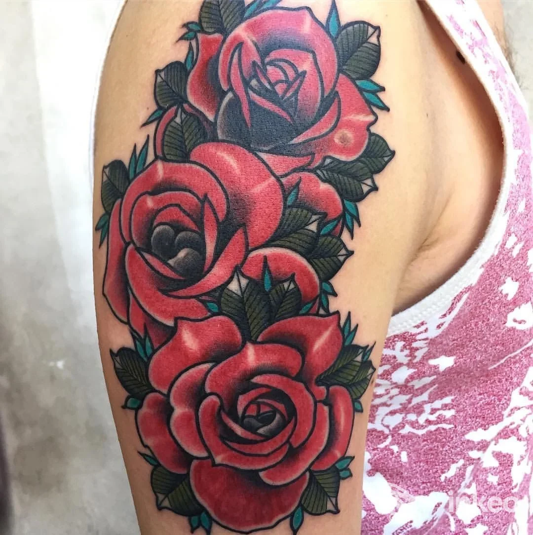 Tatuaggio a colori di tre rose sovrapposte sull'alto braccio, fotografia dello studio Liquid EyE Tattoo Shop a Forlì.