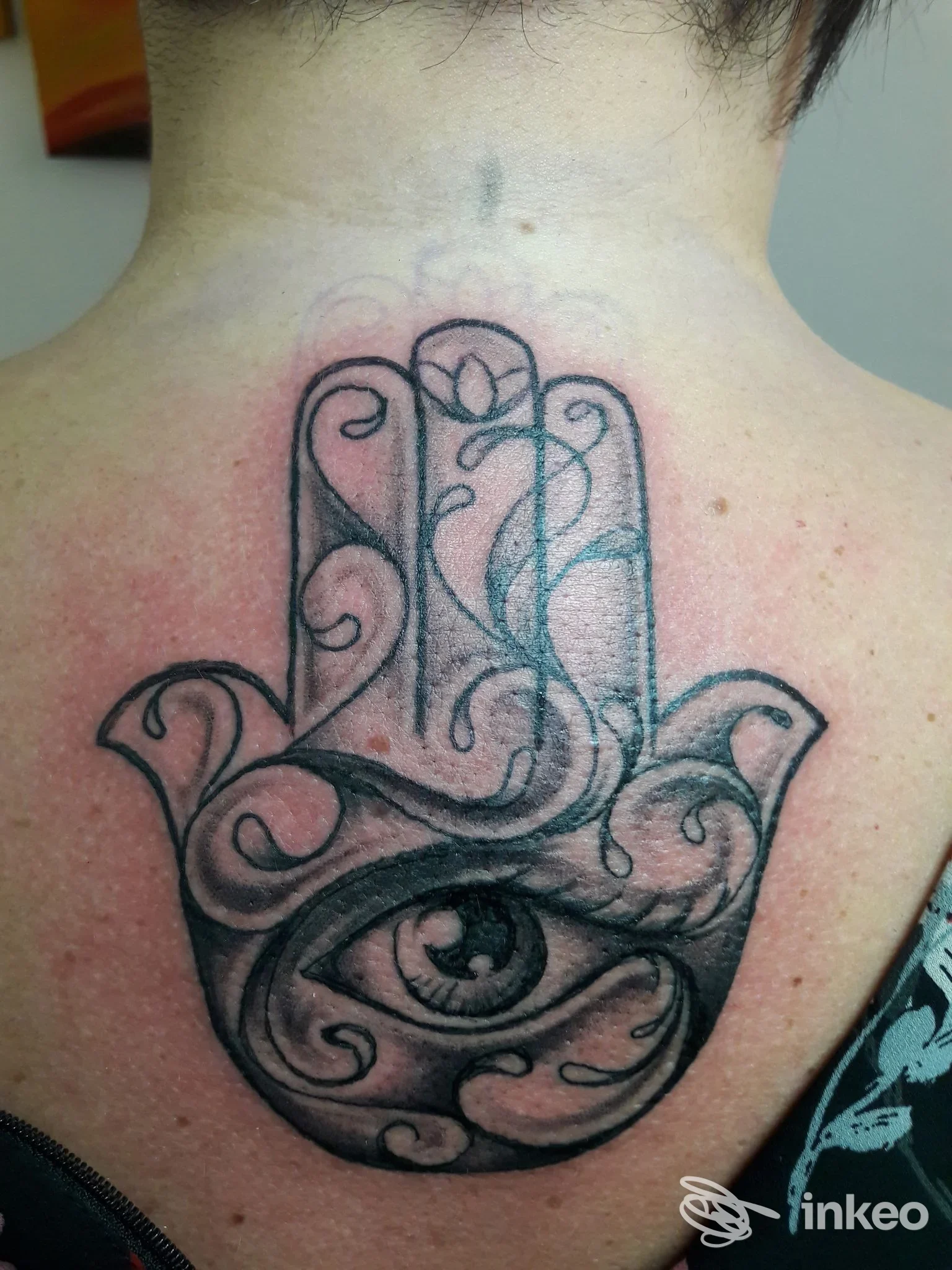 Tatuaggio Hamsa in nero sulla parte alta della schiena, lavoro eseguito da Planet Tattoo a Parma; pelle leggermente arrossata attorno al tratto.