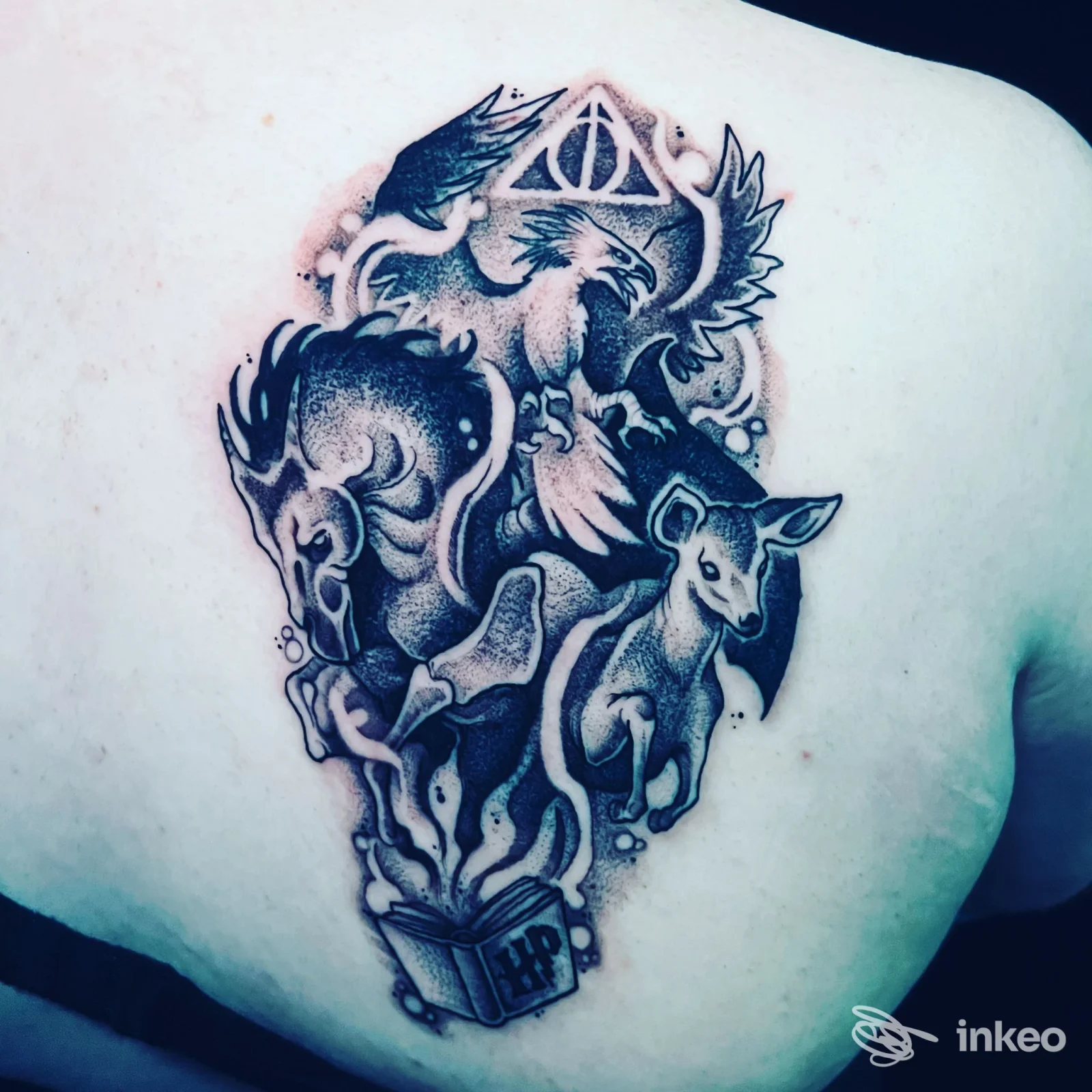Tatuaggio black/grey sulla scapola sinistra con figure animalesche e libro, foto fornita da Alchemica Tattoo, Rimini.