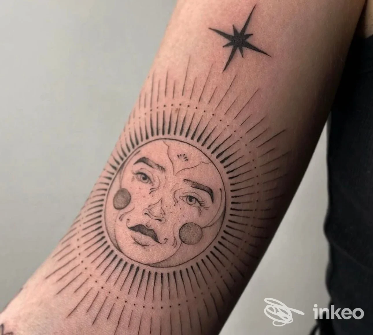 Tatuaggio a inchiostro nero di un volto solare sull'avambraccio, foto caricata dallo studio Alchemica Tattoo a Rimini.