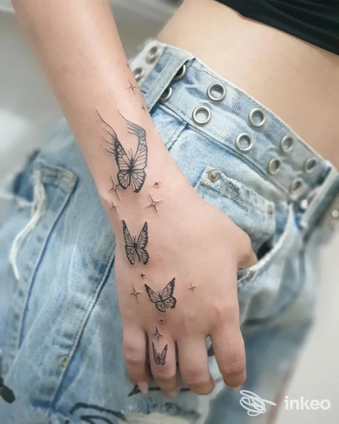 Dettaglio di mano tatuata con diverse farfalle nere, fotografia per Oksy Art Tattoo a Rimini.