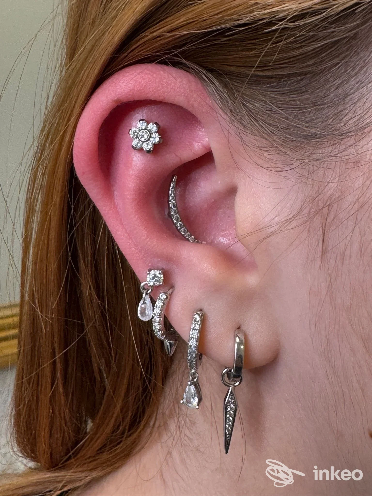 Primo piano di orecchio con più piercing gioiello al lobo, conch e helix, foto per portfolio T.Beautyink Modena