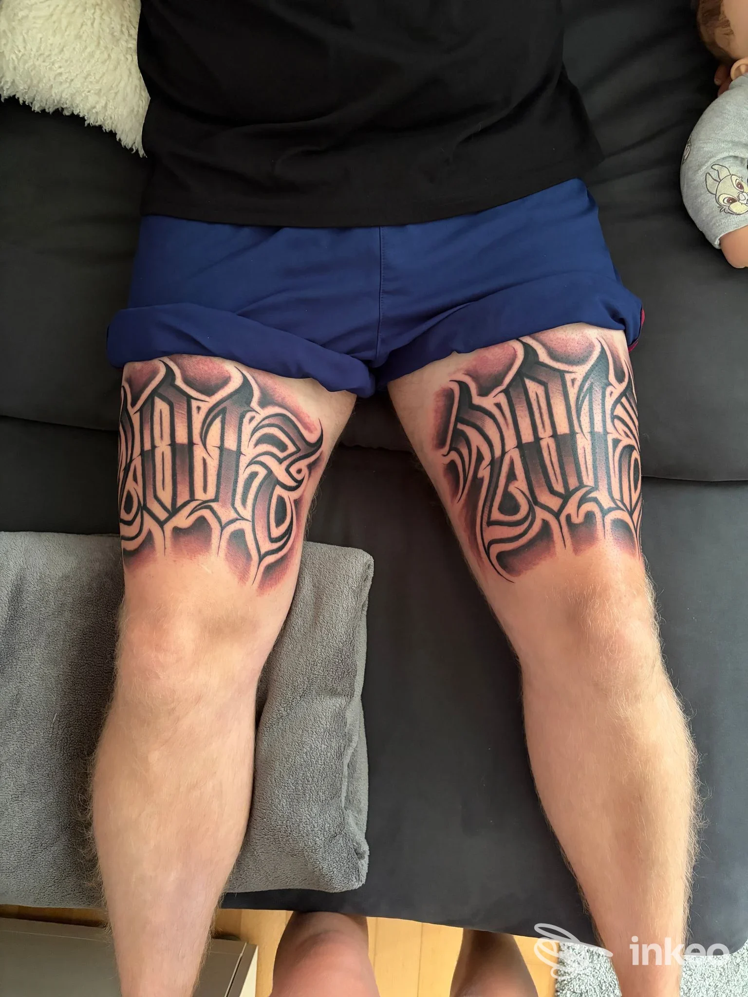 Due cosce con grandi tatuaggi lettering in stile blackwork, foto dall'alto. Goodfella Tattoo Studio, Rimini.