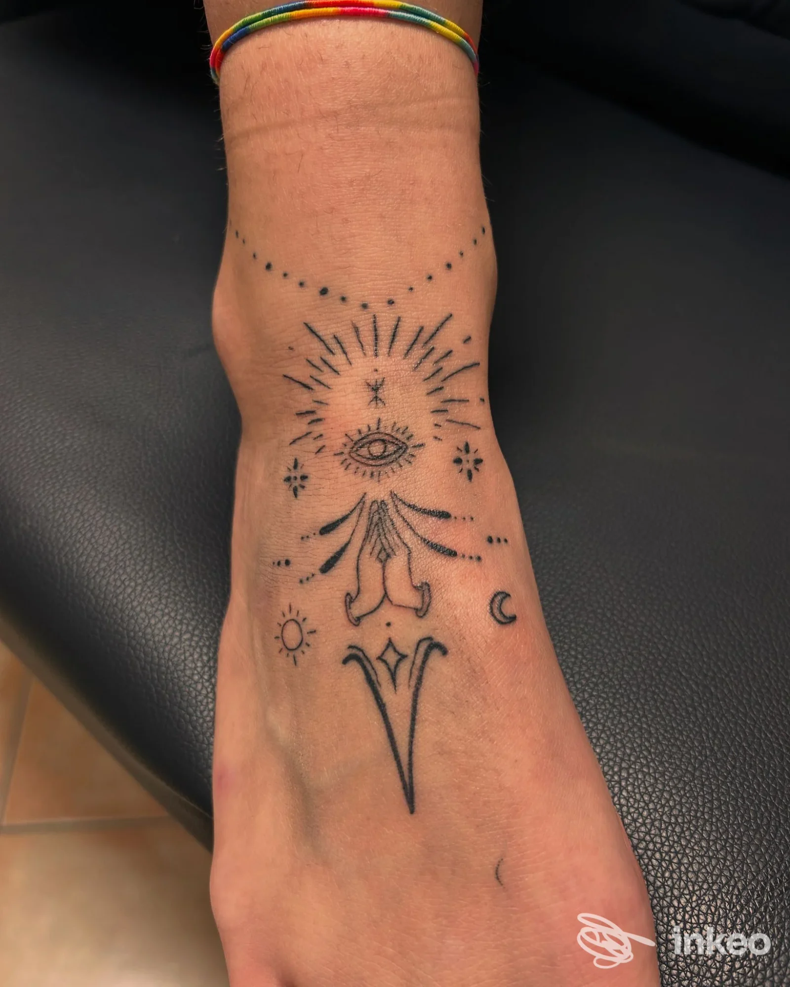 Tatuaggio nero a linee e puntinato sul dorso del piede con occhio centrale e simboli, eseguito da Black Panther tattoo&piercing a Reggiolo.