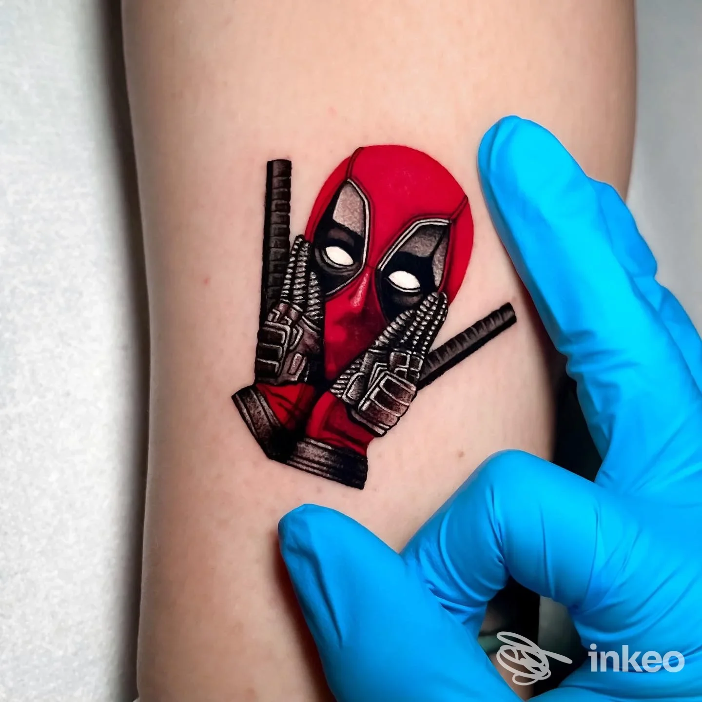 Tatuaggio Deadpool su avambraccio fotografato in studio, immagine fornita da Blu Banana Tattoo Studio a Cesenatico.