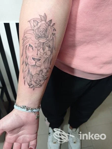 Tatuaggio di leone e fiori sull'avambraccio, lavoro in bianco e nero realizzato da Lady Bulbo Lab a Calerno.