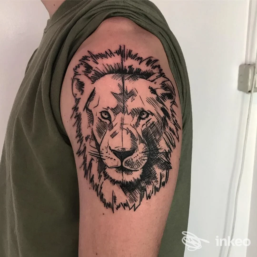Primo piano di un tatuaggio a linework raffigurante la testa di un leone sul deltoide, eseguito da Don’t Tell Mama, Parma, su pelle reale.