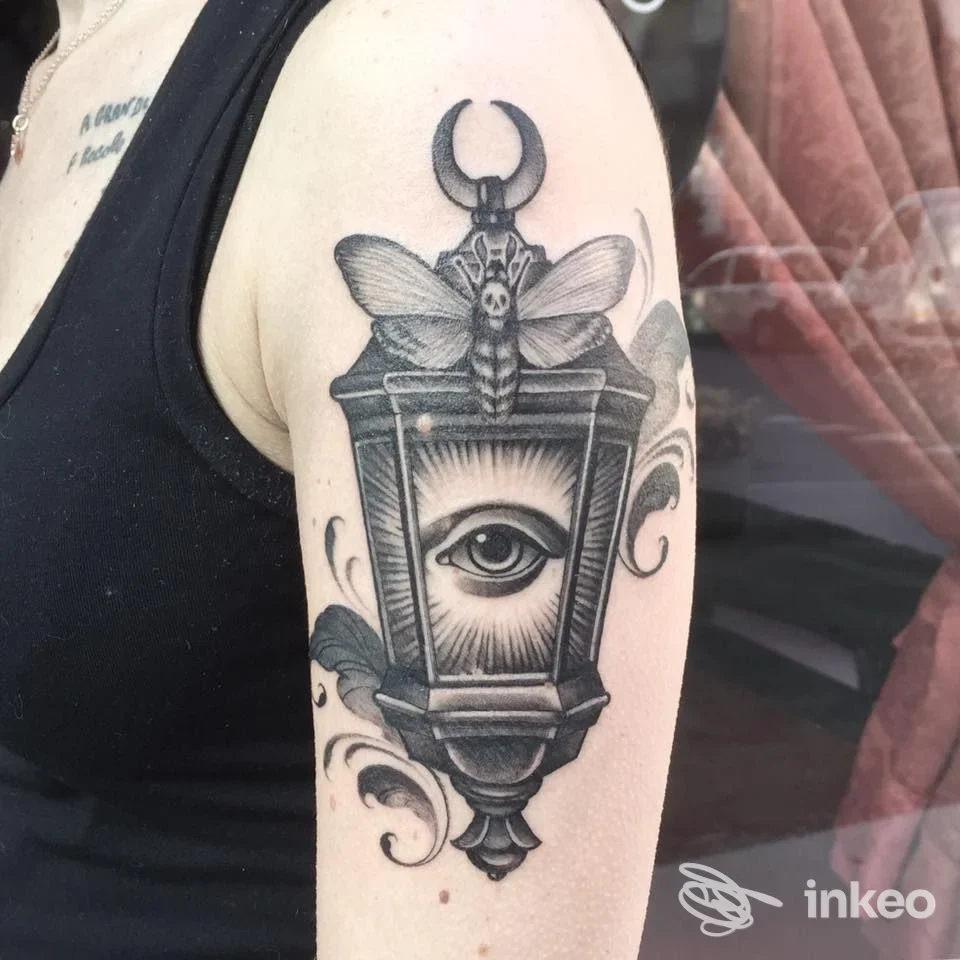 Tatuaggio lanterna con occhio e falena sul braccio superiore, realizzato da Don’t Tell Mama a Parma.