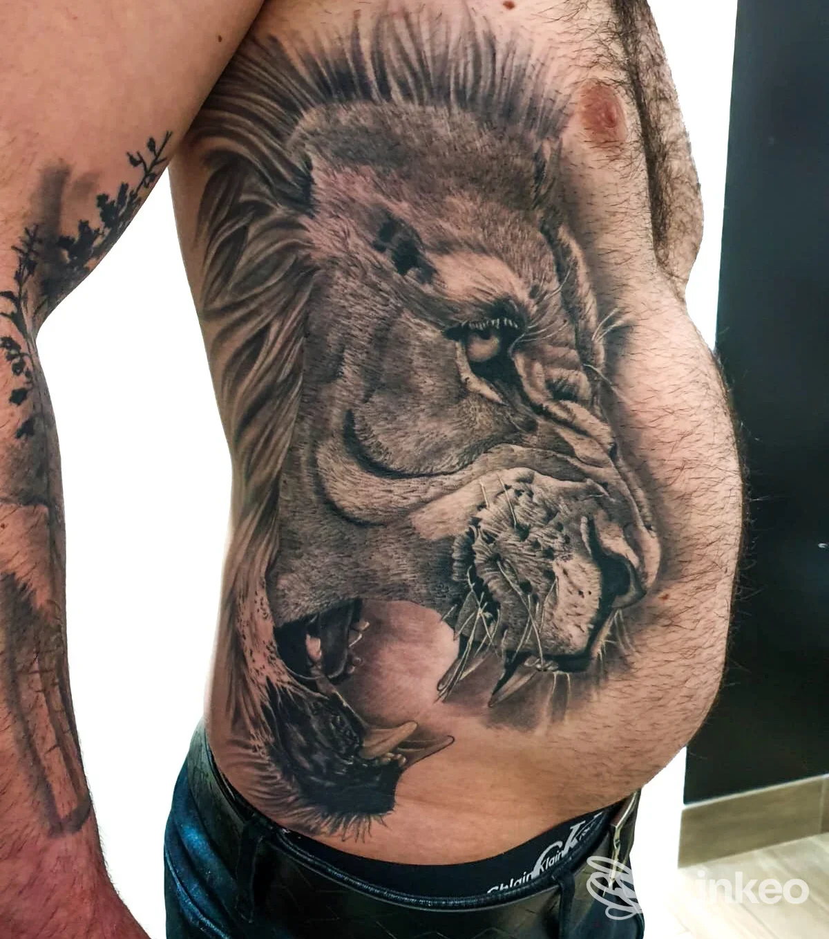 Tatuaggio realistico di leone sul fianco destro di un uomo, eseguito da Dirty Mind Tattoo Studio a San Nicolò.