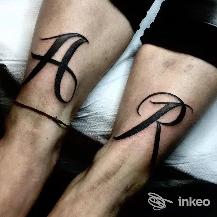 Due grandi lettere calligrafiche tatuate in nero su due arti affiancati, Teenage Dirtbag, Pavullo Nel Frignano.
