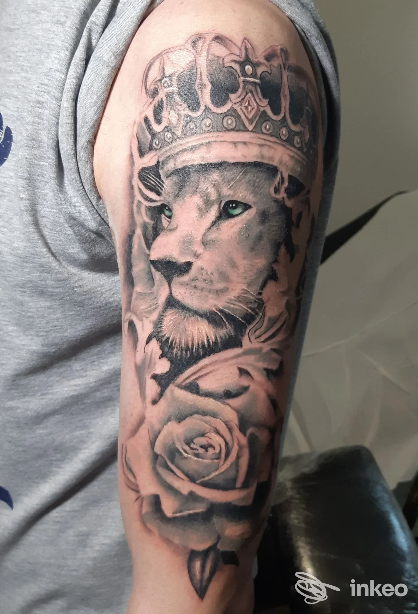Tatuaggio realistico su braccio superiore: leone con corona e rosa. King Tattoo, Collecchio.