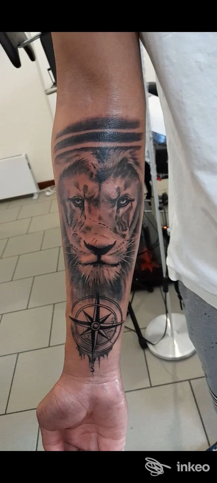 Tatuaggio realistico sul'avambraccio con volto di leone e bussola verso il polso, foto presso King Tattoo a Collecchio.