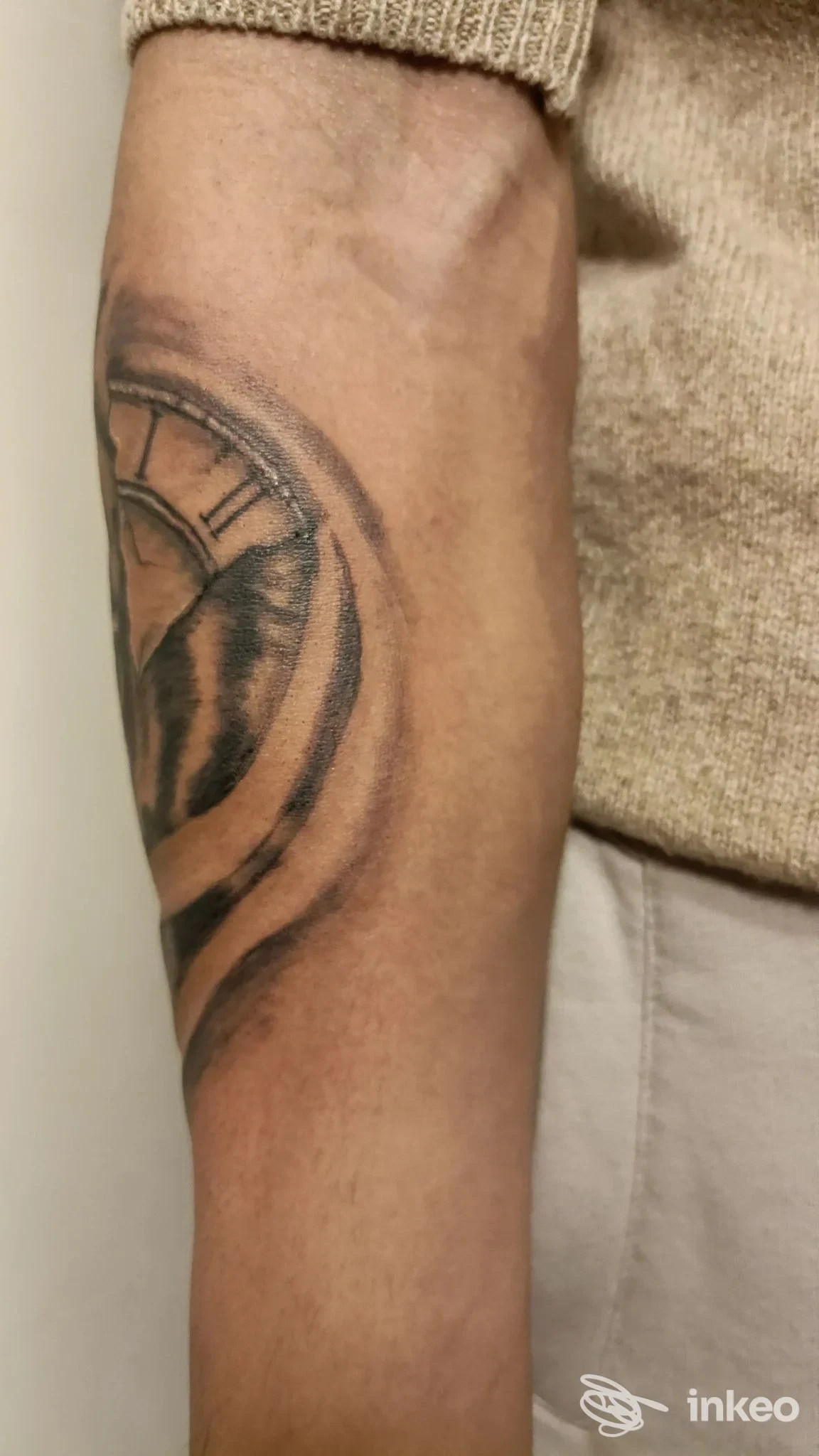 Tattoo circolare parziale sul braccio visibile, realizzato sulla pelle, senza volto visibile; immagine scattata in studio.