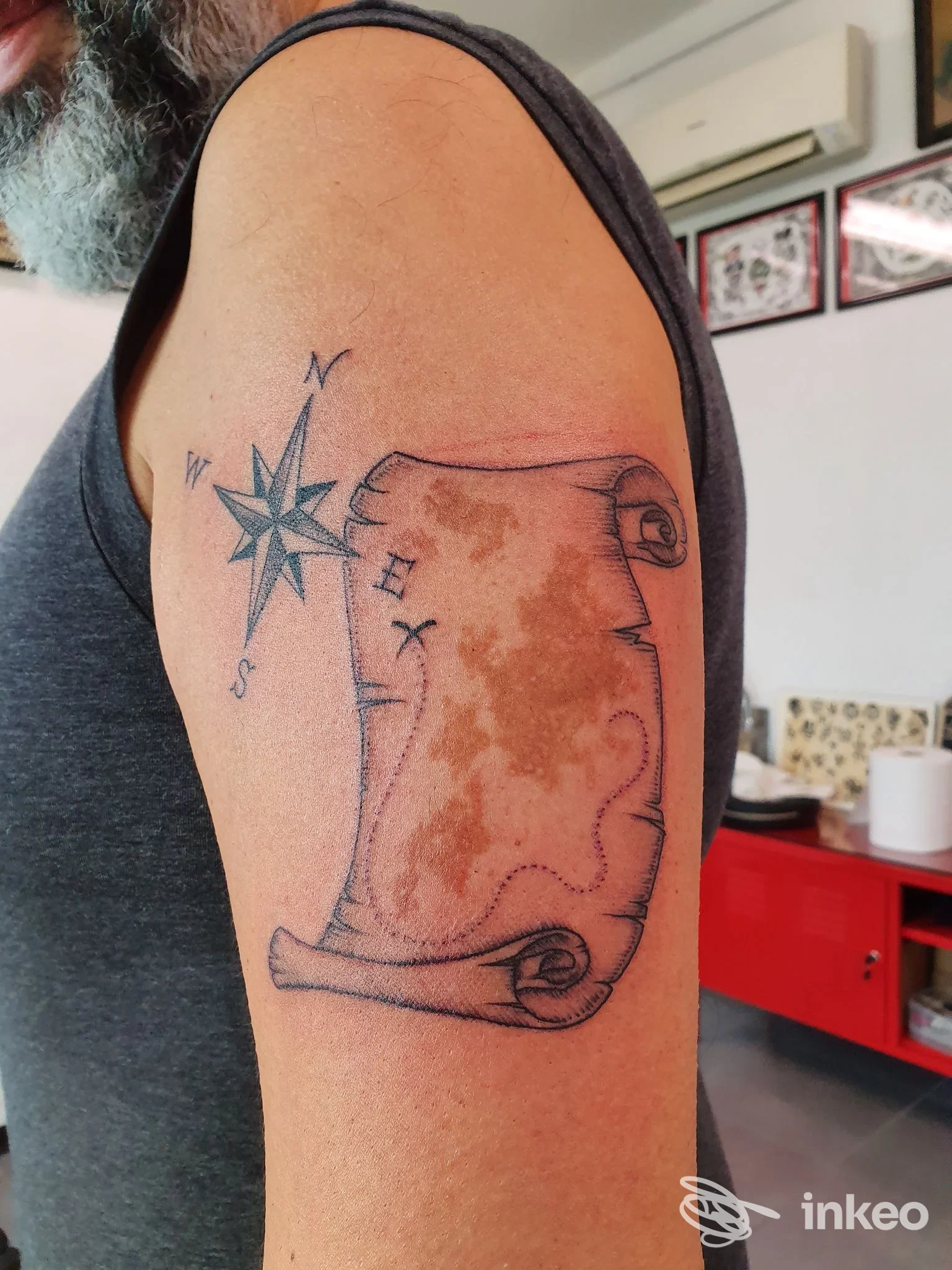 Tatuaggio a pergamena con rosa dei venti sul braccio superiore, foto dallo studio Eterno Riflesso Tattoo Studio a Gaiano.