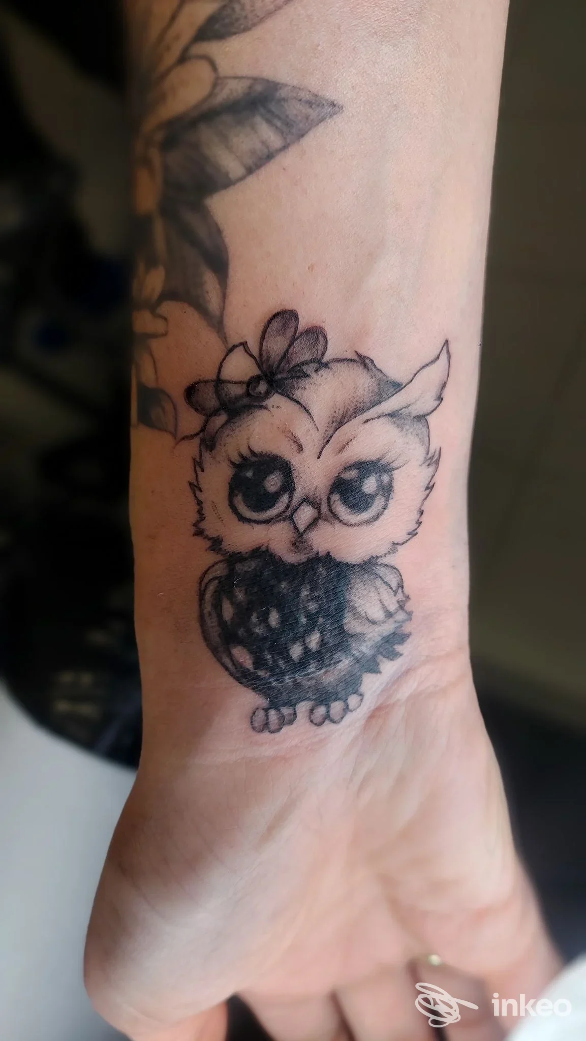 Tatuaggio gufetto in bianco e nero sul polso di una persona, fotografato in primo piano. Lupo Tattoo Art Studio, Felegara.