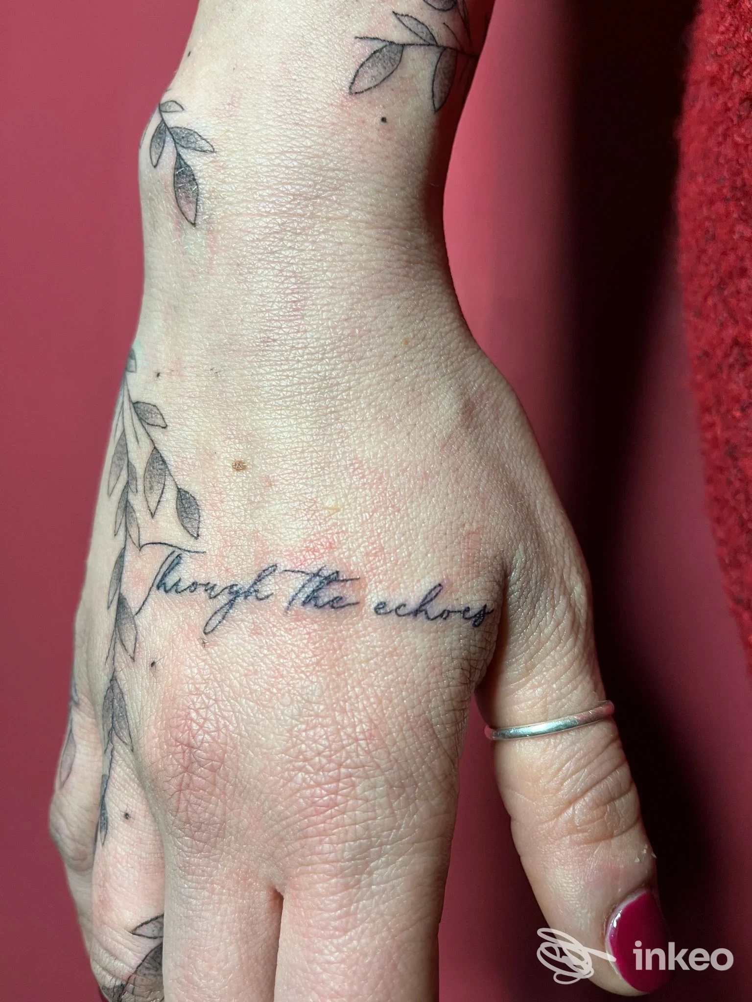 Tatuaggio di scritta corsiva sul dorso della mano con motivi a foglie, foto portfolio per Vanilla Tattooer, Santarcangelo di Romagna.