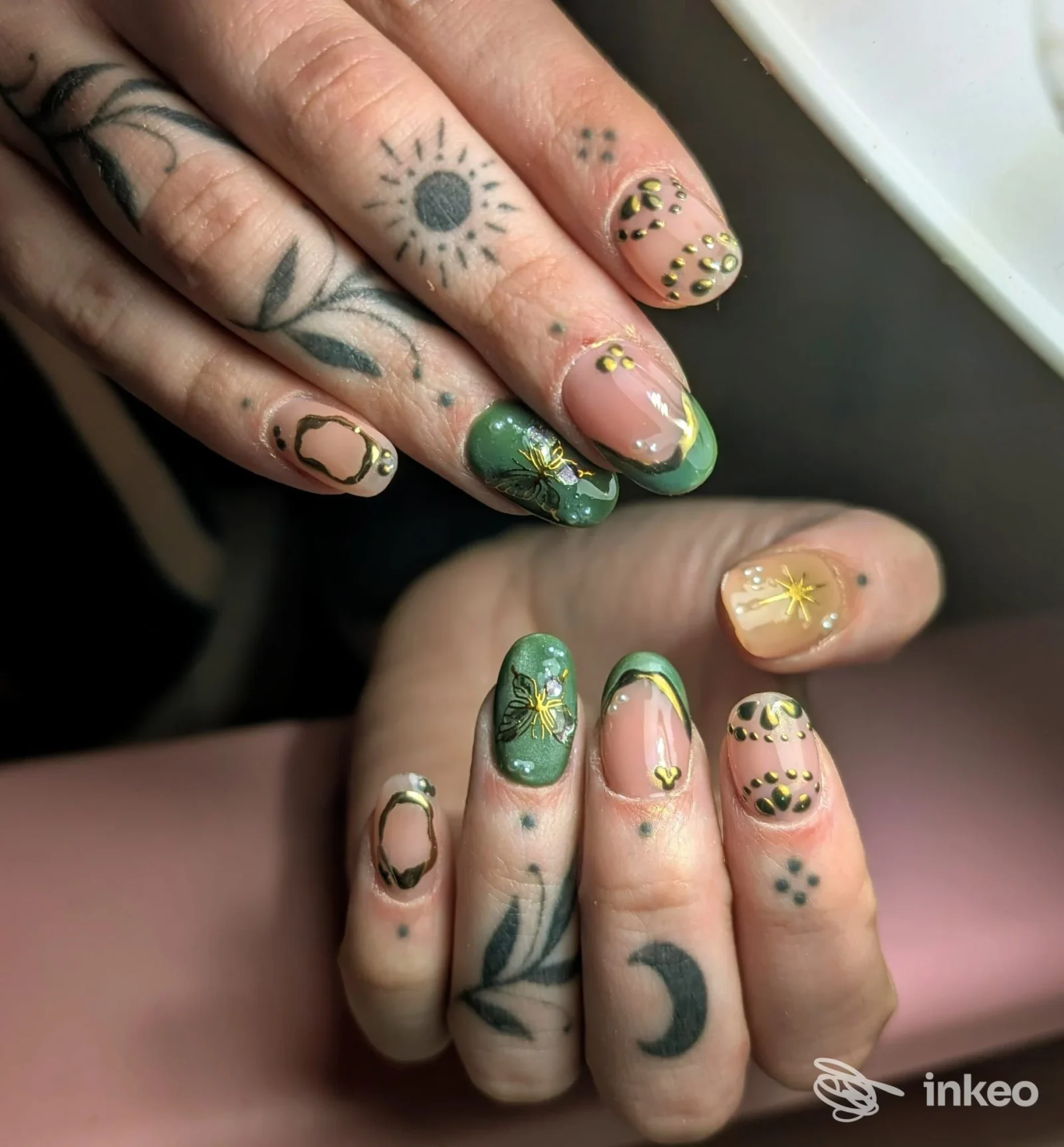 Dettaglio mani con tatuaggi sottili su dita e nail art verde/dorata, immagine da Ártemis Studio, Modena.
