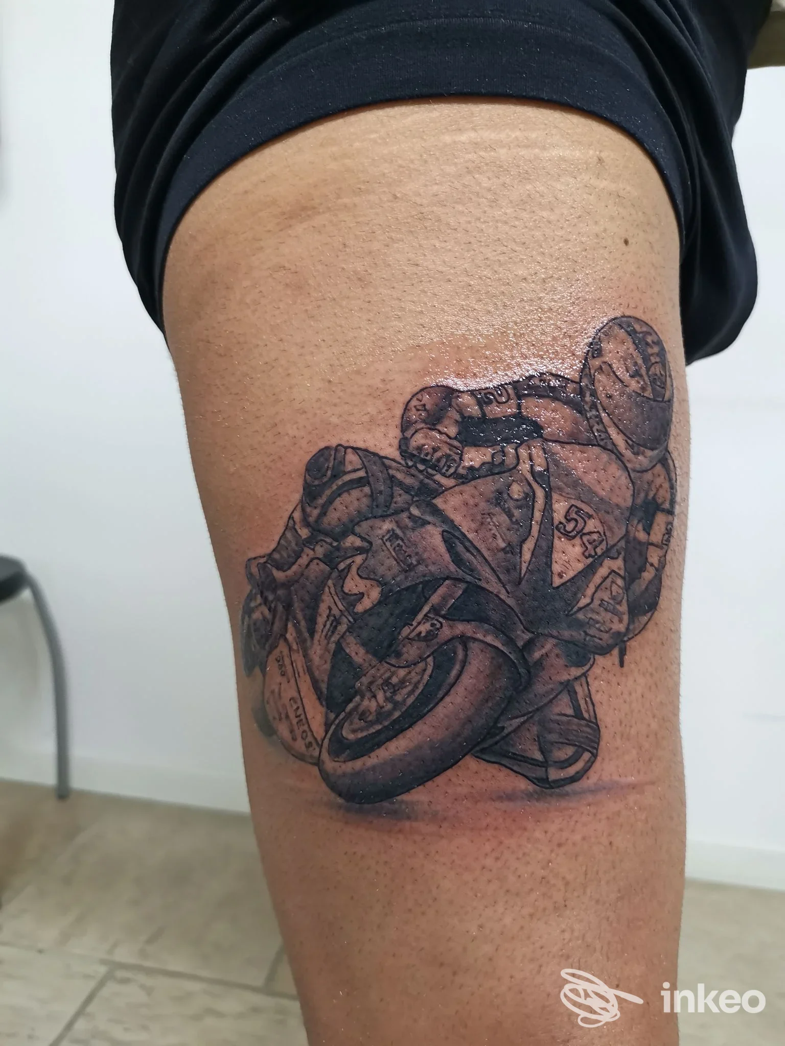Tatuaggio realistico in bianco e nero raffigurante una moto con pilota sulla parte alta della coscia, realizzato da Picti Tattoo Shop a Piacenza.