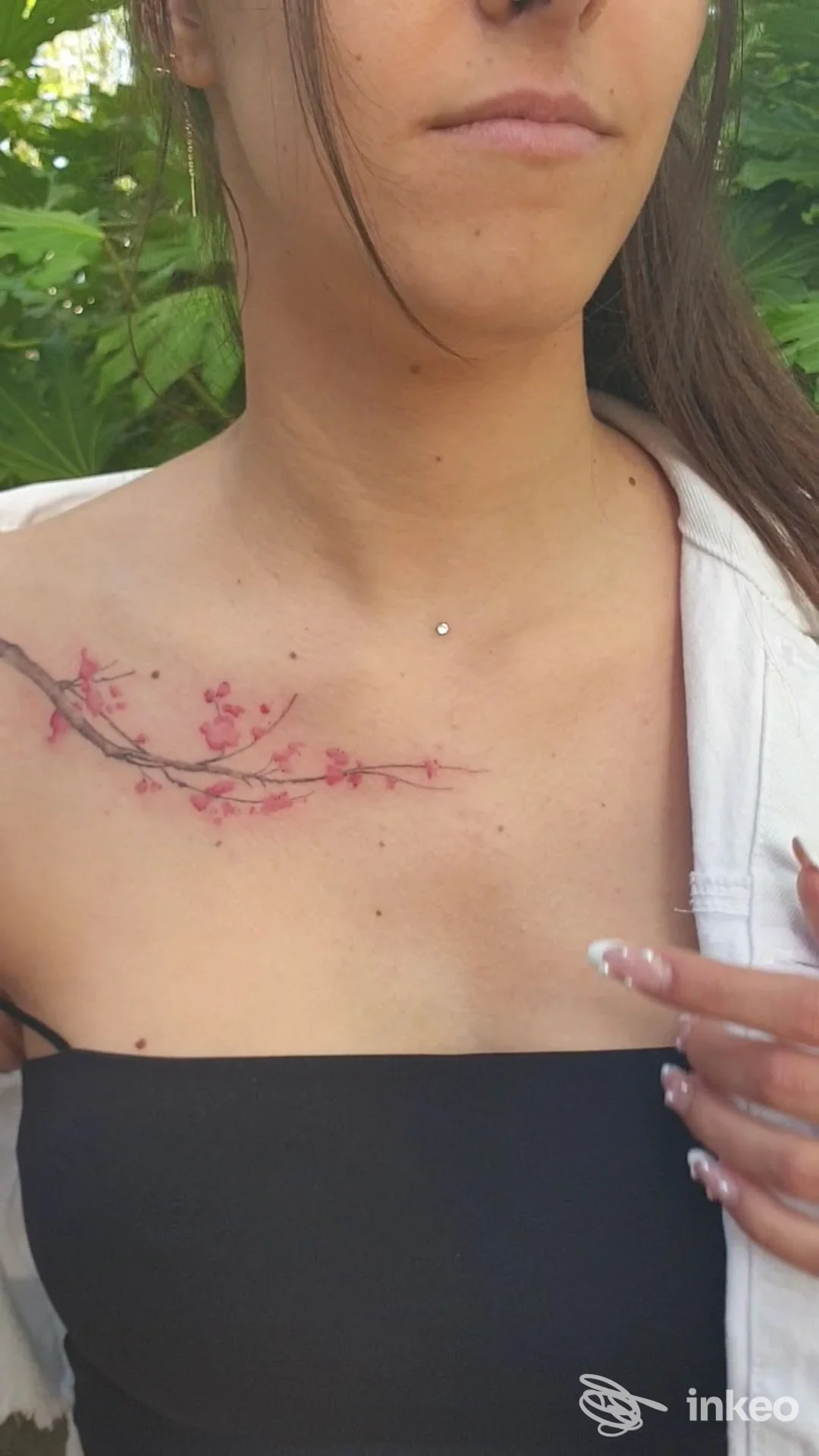 Tatuaggio floreale a ramo con fiori rosa sulla clavicola sinistra, foto di Malusi Tattoo Atelier a Cervia.