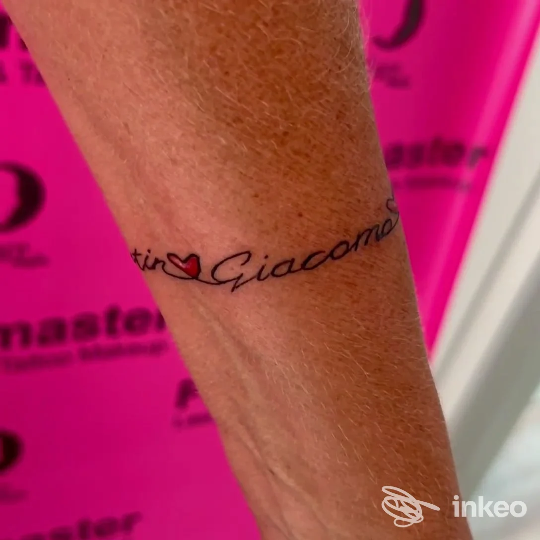 Tatuaggio sul polso/avambraccio con scritto 'Giacomo' in corsivo e un piccolo cuore rosso, scatto nello studio Facemaster a Riccione.