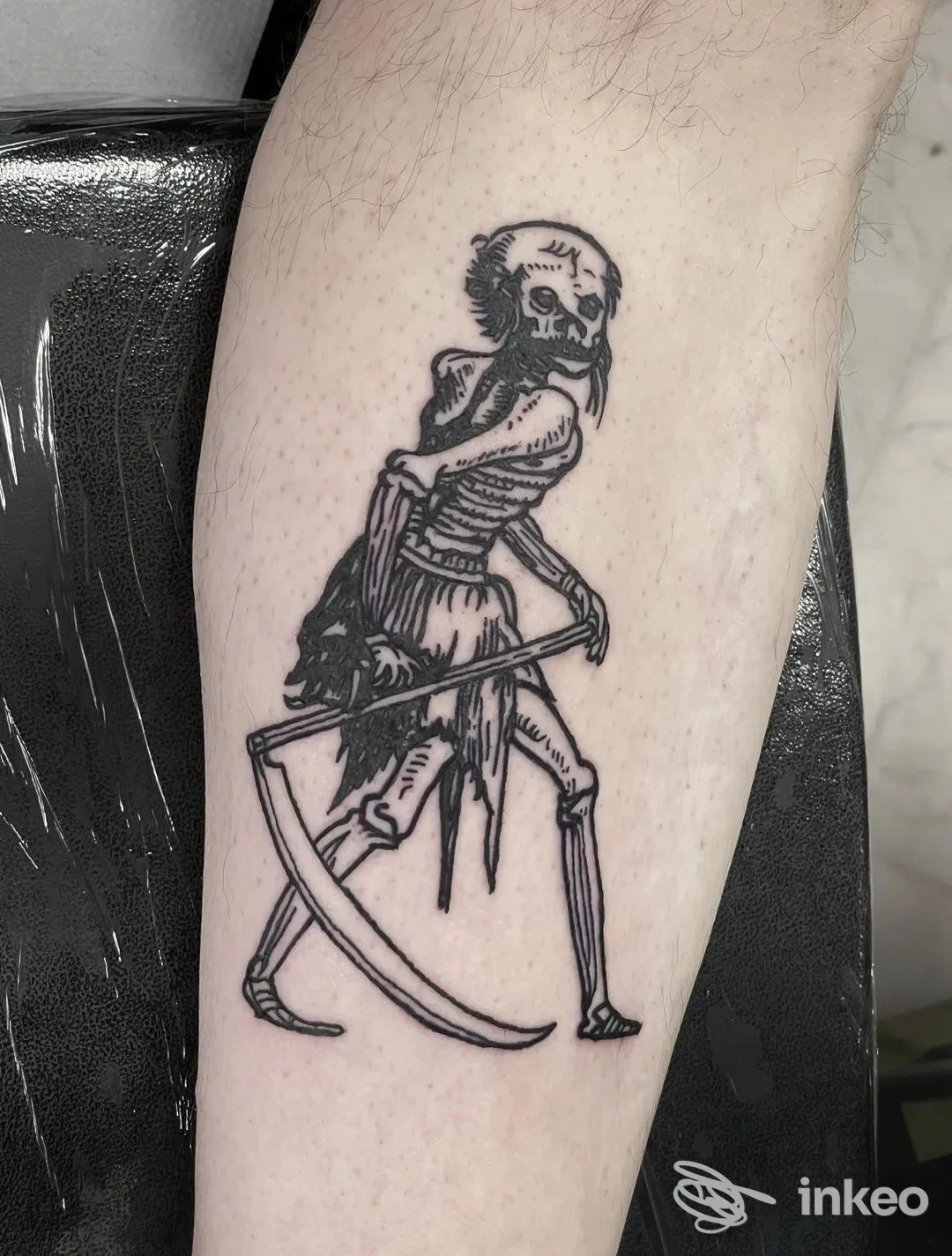 Tatuaggio in stile linework/blackwork di una figura scheletrica con falce sull'avambraccio. No Remorse Tattoo Studio, Reggio nell'Emilia.