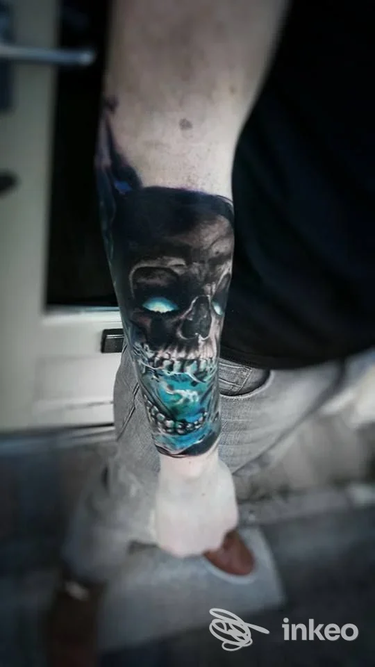 Tatuaggio realistico di teschio con accenti turchesi sull'avambraccio, foto fornita da Freak Circus Tattoo Studio a Bologna.