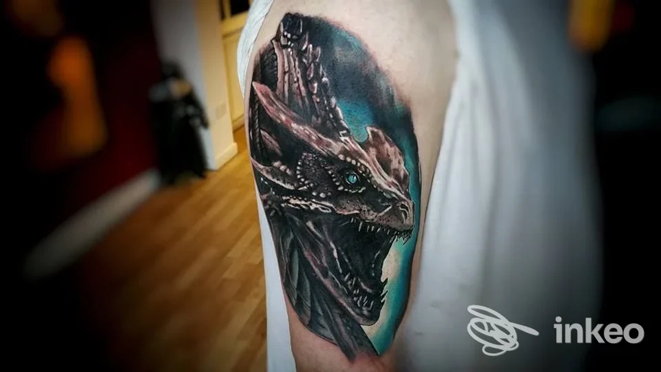 Fotografia di un tatuaggio realistico raffigurante un drago sul braccio superiore, eseguito da Freak Circus Tattoo Studio a Bologna.