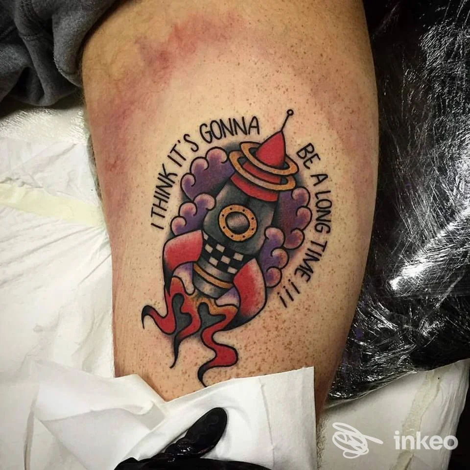 Tatuaggio colorato di un razzo con fiamme e nuvole sul polpaccio, realizzato presso Freak Circus Tattoo Studio a Bologna.