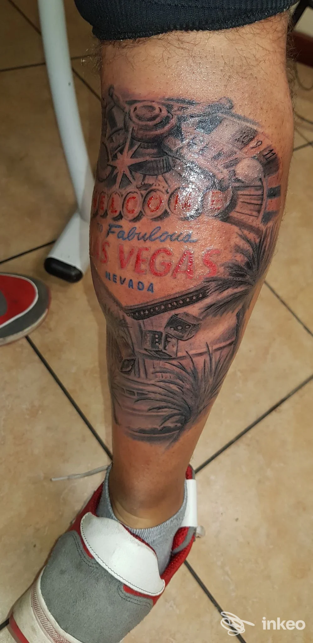 Tatuaggio esteso sul polpaccio con lettering 'Fabulous Las Vegas' e motivi in nero/grigio, scattato da Infamilia Tattoo a Sassuolo.