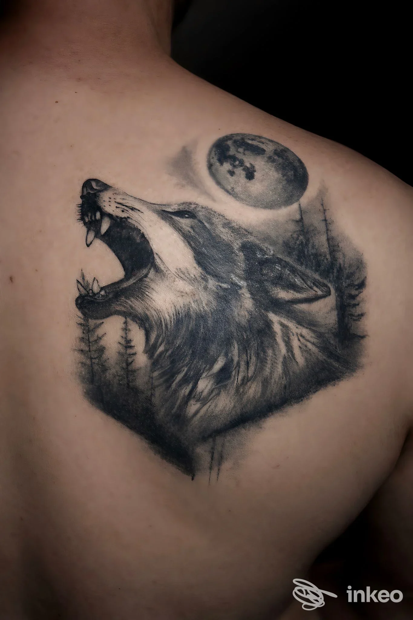 Tatuaggio realistico di un lupo ululante con luna sulla spalla/alta schiena, realizzato da Inkshady Tattoo Studio a Savignano sul Rubicone.